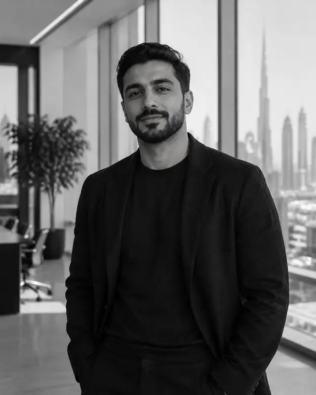Dany D, operations lead at Daut Labz, in a dark blazer in an office overlooking the Dubai skyline.